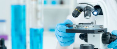 Bilimadamı ileri bilimsel laboratuvarda biyokimyasal örnekleri analiz ediyor. Tıbbi profesyonel kullanım mikroskobu virüsün mikrobiyolojik gelişimini gösteriyor. Fen laboratuvarında biyoteknoloji araştırması