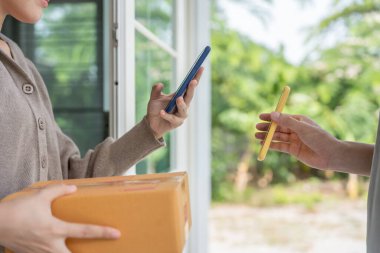 Mutlu bir gülümseme Asyalı kadın yemek parası için QR kodunu tarıyor. Teslimatçı ekspres teslimat gönderdi. Çevrimiçi dükkan, kağıt konteynır, paket servis, paket, elektronik para, dijital transfer