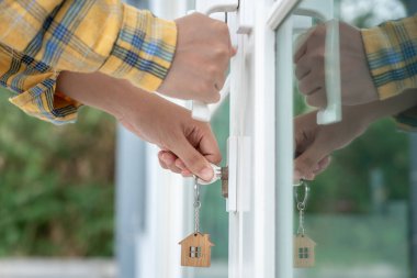 Evin kilidini açmak için ev sahibi anahtarı kapıya takılı. Kira ve satış için ikinci el ev. Sahibi el ile yeni ev için kapı ipoteğini açar, satın alır, satar, yeniler, yatırım, sahip, estat