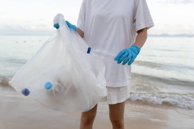 Okyanusu kurtar. Gönüllü olarak plajdaki çöpleri topluyor ve plastik şişeler suda yaşayan canlılara zarar gelmesini engelliyor. Dünya, Çevre, Yeşilci Gezegen, küresel ısınmayı azaltmak, Dünya 'yı kurtarmak