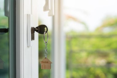 Landlord key for unlocking house is plugged into the door. Second hand house for rent and sale. keychain is blowing in the wind. mortgage for new home, buy, sell, renovate, investment, owner, estate
