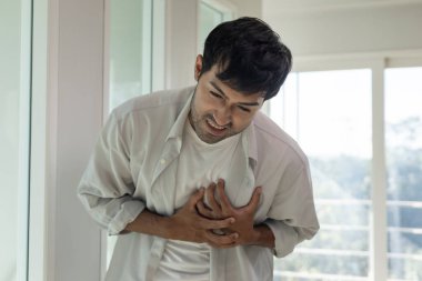 Göğüs kafesinde kalp krizi belirtileri var. Asyalı bir adamın göğüs ağrısı var. Kalp hastalığından, sızıntıdan, genişlemeden, genişlemiş kalp krizinden, göğsüne acı veren bir ifadeyle bastırılmış.