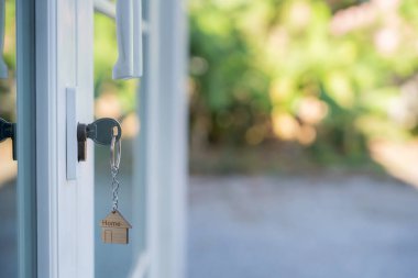 Landlord key for unlocking house is plugged into the door. Second hand house for rent and sale. keychain is blowing in the wind. mortgage for new home, buy, sell, renovate, investment, owner, estate