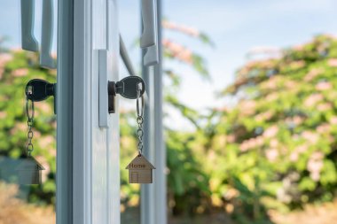 Evin kilidini açmak kapıya takılı. Kira ve satış için ikinci el ev. Anahtarlık rüzgarda savruluyor. Yeni ev için ipotek, satın alma, satma, yenileme, yatırım, sahip, mülk