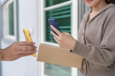 Mutlu bir gülümseme Asyalı kadın yemek parası için QR kodunu tarıyor. Teslimatçı ekspres teslimat gönderdi. Çevrimiçi dükkan, kağıt konteynır, paket servis, paket, elektronik para, dijital transfer