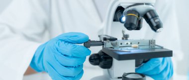 Bilimadamı ileri bilimsel laboratuvarda biyokimyasal örnekleri analiz ediyor. Tıbbi profesyonel kullanım mikroskobu virüsün mikrobiyolojik gelişimini gösteriyor. Fen laboratuvarında biyoteknoloji araştırması