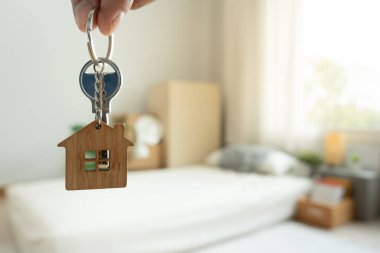 Moving house, relocation. Man hold key house keychain in new apartment, inside the room was a cardboard box containing personal belongings and furniture. move in the apartment or condominium