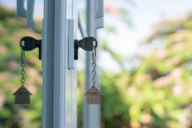Landlord key for unlocking house is plugged into the door. Second hand house for rent and sale. keychain is blowing in the wind. mortgage for new home, buy, sell, renovate, investment, owner, estate