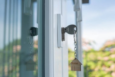 Landlord key for unlocking house is plugged into the door. Second hand house for rent and sale. keychain is blowing in the wind. mortgage for new home, buy, sell, renovate, investment, owner, estate
