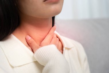 Asyalı kadın boğazı ağrıdığı için boynuna takıldı. Dişi bademcik iltihabı iltihaba neden olur. Su alarak, antibiyotik alarak, doktora, virüse, korona virüsüne, gribe, gribe danışarak tedavi olunur.