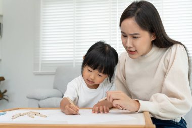 Mutlu Asyalı anne küçük kız için boya öğreniyor. Komik aile evde mutlu ve heyecanlı. Anne ve kızı birlikte vakit geçiriyorlar. Tatil, etkinleştir