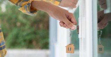 Evin kilidini açmak için ev sahibi anahtarı kapıya takılı. Kira ve satış için ikinci el ev. Sahibi yeni ev, satın al, sat, yenile, yatırım, sahip, mülk