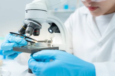 Bilimadamı ileri bilimsel laboratuvarda biyokimyasal örnekleri analiz ediyor. Tıbbi profesyonel kullanım mikroskobu virüsün mikrobiyolojik gelişimini gösteriyor. Fen laboratuvarında biyoteknoloji araştırması.