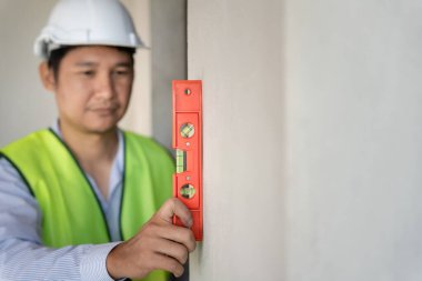 Contactor or engineer is inspecting construction and quality assurance new house using a level. Engineers or architects or contactor work to build the house before handing it over to the homeowner