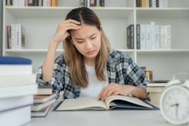 Asian student woman have anxiety because of exams, female prepare for test and learning lessons in the library. stress, despair, haste, misunderstanding reading, discouraged, expectation, knowledge
