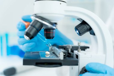 Bilimadamı ileri bilimsel laboratuvarda biyokimyasal örnekleri analiz ediyor. Tıbbi profesyonel kullanım mikroskobu virüsün mikrobiyolojik gelişimini gösteriyor. Fen laboratuvarında biyoteknoloji araştırması