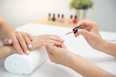 Kadın, güzellik merkezinde profesyonel güzellik manikürü ile bakım hizmeti alıyor. Güzellik salonunda jöle tedavisi için tırnak törpüsü kullanın. Manikürcü, çivi müşterisini güzelleştirir. vücut bakımı spa tedavisi