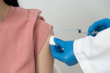 Kadın salgını önlemek için aşı oluyor. Tıp merkezindeki bir hemşire ya da doktordan bir doz bağışıklık aşısı al. Temel aşı, alternatif aşı, riskin artması için aşı.