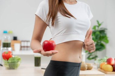 İnce vücutlu Asyalı kadınlar sağlıklı yiyecekleri, diyet yapan kadınlar diyet için kırmızı elmayı seçer. Sağlıklı yiyecekler. kilo kaybı, denge, kontrol, yağ, düşük kalori, rutinler, egzersiz, vücut şekli.