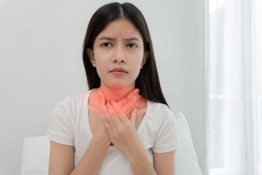 Asyalı kadın boğazı ağrıdığı için boynuna takıldı. Dişi bademcik iltihabı iltihaba neden olur. Su alarak, antibiyotik alarak, doktora, virüse, korona virüsüne, gribe, gribe danışarak tedavi olunur.