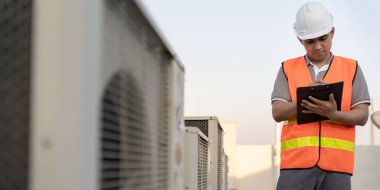 Asyalı bakım mühendisi fabrikanın çatısında çalışıyor. Müteahhit kompresör sistemini denetleyecek ve inşaatta havalandırma sistemi kurmayı planlıyor. Kontrol listesi, müfettiş, kontrol