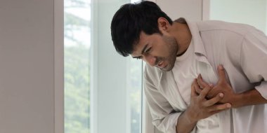 Göğüs kafesinde kalp krizi belirtileri var. Asyalı bir adamın göğüs ağrısı var. Kalp rahatsızlığı, sızıntı, genişleme, kalp büyümesi, göğsüne acı verici bir ifadeyle bastırma.