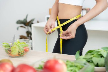 Diyet ve diyet. Güzel, ince kadın vücut ölçüsü fitness için şerit kullanır. Spor elbiseli bir kadın sağlıklı yaşam için kilo verme hedefine, zayıflığa, ince belliye, beslenme uzmanına ulaşır..