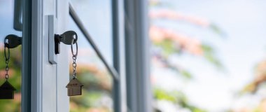 Landlord key for unlocking house is plugged into the door. Second hand house for rent and sale. keychain is blowing in the wind. mortgage for new home, buy, sell, renovate, investment, owner, estate