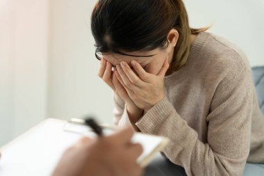 Akıl sağlığı sorunları olan bir kadın danışmanlık yapıyor. Psikiyatrist tedavi için hastanın durumunu kaydediyor. teşvik, sevgi ve aile sorunu, bipolar, depresyon hastası, intiharı koru