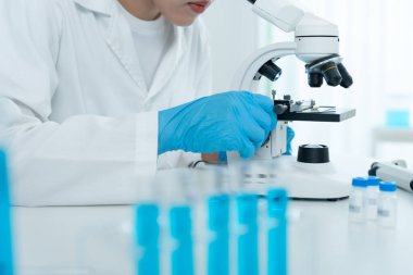 Bilimadamı ileri bilimsel laboratuvarda biyokimyasal örnekleri analiz ediyor. Tıbbi profesyonel kullanım mikroskobu virüsün mikrobiyolojik gelişimini gösteriyor. Fen laboratuvarında biyoteknoloji araştırması.