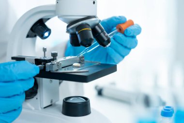 Bilimadamı ileri bilimsel laboratuvarda biyokimyasal örnekleri analiz ediyor. Tıbbi profesyonel kullanım mikroskobu virüsün mikrobiyolojik gelişimini gösteriyor. Fen laboratuvarında biyoteknoloji araştırması.