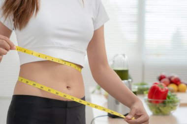 Diyet ve diyet. Güzel, ince kadın vücut ölçüsü. Spor elbiseli bir kadın sağlıklı yaşam için kilo verme hedefine, zayıflığa, ince belliye, beslenme uzmanına ulaşır..