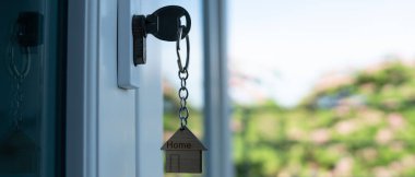 Landlord key for unlocking house is plugged into the door. Second hand house for rent and sale. keychain is blowing in the wind. mortgage for new home, buy, sell, renovate, investment, owner, estate