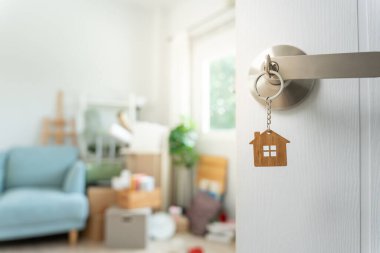 Moving house, relocation. The key was inserted into the door of the new house, inside the room was a cardboard box containing personal belongings and furniture. move in the apartment or condominium