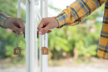 Evin kilidini açmak için ev sahibi anahtarı kapıya takılı. Kira ve satış için ikinci el ev. Sahibi el ile yeni ev için kapı ipoteğini açar, satın alır, satar, yeniler, yatırım, sahip, estat