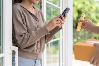 Mutlu Asyalı kadın ödeme için QR kodunu tarıyor. Teslimatçı ekspres teslimat gönderdi. Çevrimiçi dükkan, kağıt konteynır, paket servis, paket, elektronik para, dijital transfer