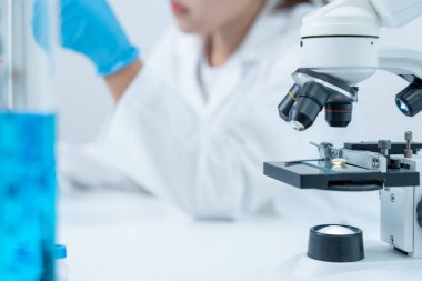 Bilimadamı ileri bilimsel laboratuvarda biyokimyasal örnekleri analiz ediyor. Tıbbi profesyonel kullanım mikroskobu virüsün mikrobiyolojik gelişimini gösteriyor. Fen laboratuvarında biyoteknoloji araştırması.