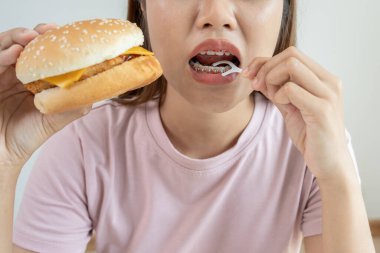 Diş bakımı tedavisi. Kadın diş telleri yemek parçacıklarını temizlemek için diş ipi kullanır. Dişlerin üzerindeki metal bileklikler. Genç, diş tellerinden sonra özen gösteren, ortodontiye güvenen. Ağız kokusunun ve diş çürüğünün giderilmesi.