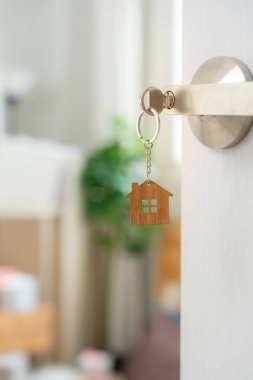 Moving house, relocation. The key was inserted into the door of the new house, inside the room was a cardboard box containing personal belongings and furniture. move in the apartment or condominium