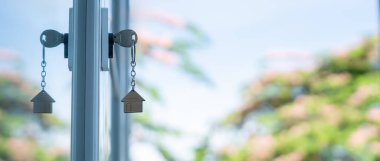 Landlord key for unlocking house is plugged into the door. Second hand house for rent and sale. keychain is blowing in the wind. mortgage for new home, buy, sell, renovate, investment, owner, estate