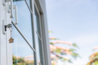 Landlord key for unlocking house is plugged into the door. Second hand house for rent and sale. keychain is blowing in the wind. mortgage for new home, buy, sell, renovate, investment, owner, estate