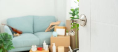 Moving house, relocation. The key was inserted into the door of the new house, inside the room was a cardboard box containing personal belongings and furniture. move in the apartment or condominium