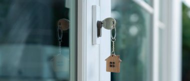 Landlord key for unlocking house is plugged into the door. Second hand house for rent and sale. keychain is blowing in the wind. mortgage for new home, buy, sell, renovate, investment, owner, estate