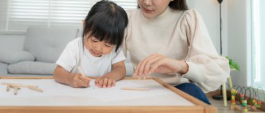 Mutlu Asyalı anne küçük kız için boya öğreniyor. Komik aile evde mutlu ve heyecanlı. Anne ve kızı birlikte vakit geçiriyorlar. Tatil, Etkinlik