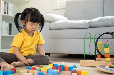Mutlu Asyalı çocuk oyun oynuyor ve oyuncak bloklarını öğreniyor. Çocuklar evde çok mutlu ve heyecanlı. Çocuk oyun, etkinlik, gelişme ve dikkat eksikliği hiperaktivite bozukluğuyla çok iyi vakit geçiriyor