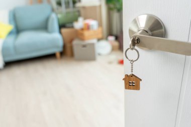 Moving house, relocation. The key was inserted into the door of the new house, inside the room was a cardboard box containing personal belongings and furniture. move in the apartment or condominiu