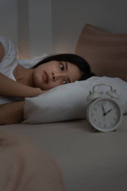 Geç saatte yatakta uyuyan bir kadın uykusuzluk çekmeye çalışıyor, uykusuz ya da bir kabusta korkmuş, üzgün ve stresli görünüyor. Yorgun ve baş ağrısı ya da gecenin bir yarısı uyanan migren..