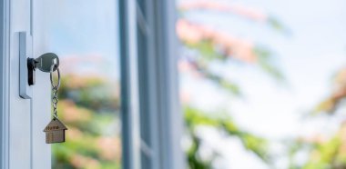 Landlord key for unlocking house is plugged into the door. Second hand house for rent and sale. keychain is blowing in the wind. mortgage for new home, buy, sell, renovate, investment, owner, estate
