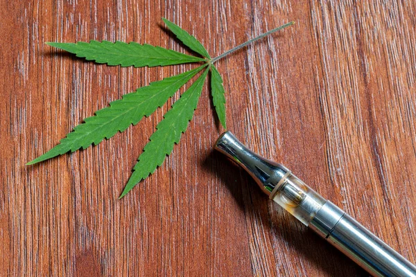 大麻の葉の背景を持つCbd気化器 — ストック写真
