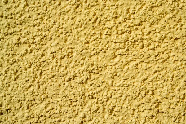 Textured plaster on a wall in the color yellow, texture background